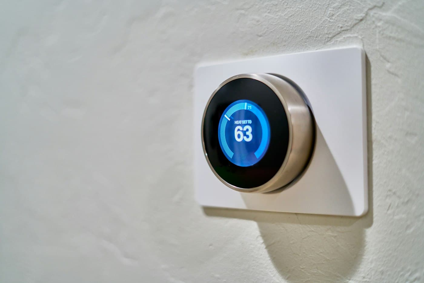 A smart thermostat on a wall showing the target temperature